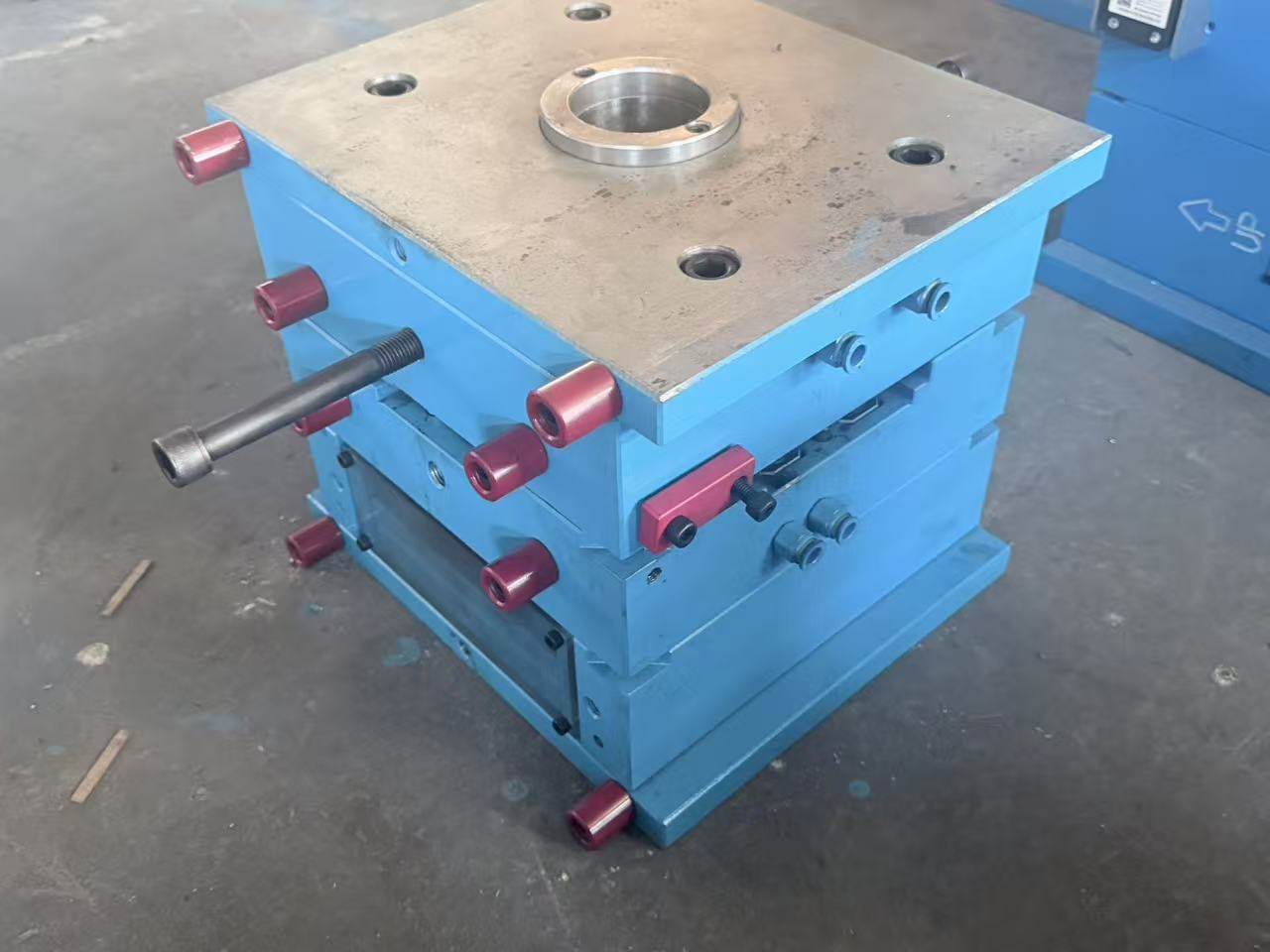 Closed blue injection mold photographed on a workshop floor